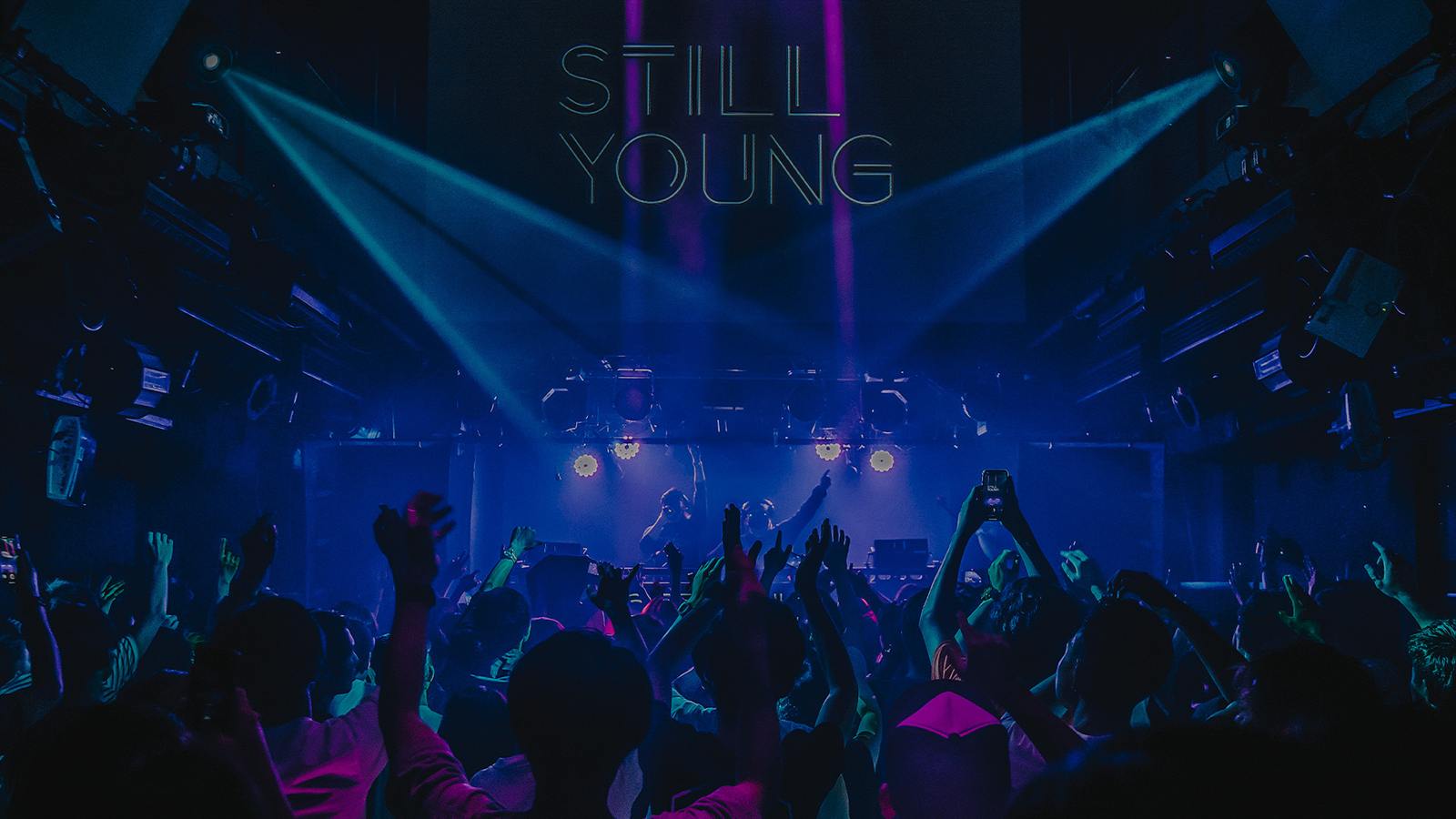Still Young performing to a crowd under blue and violet beams