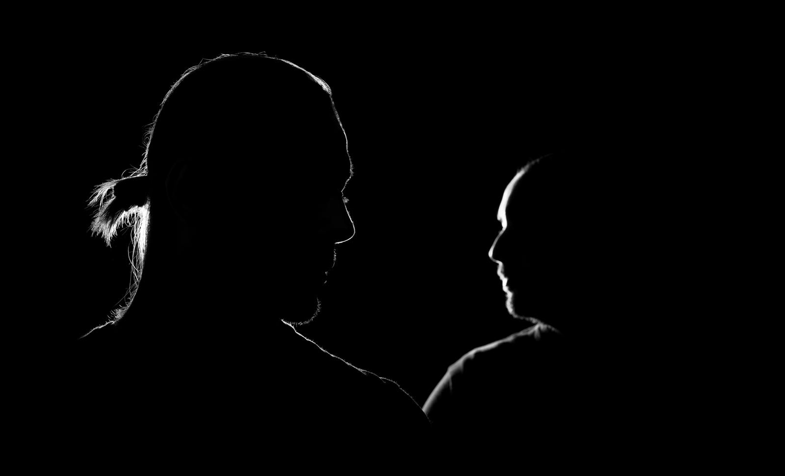 Rim-lit portrait of the Still Young duo, face to face in darkness